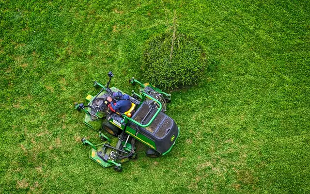 overhead image of a man cutting grass on a mower